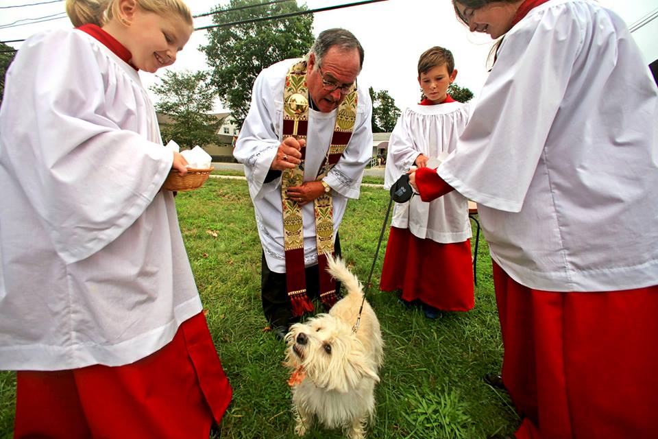 Father Dinoto blessing a dog during the St. Francis blessing ceremony on the St. Johns Green.