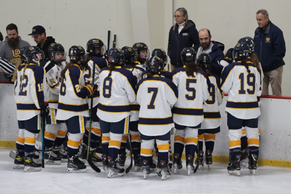 The Woodstock Academy girls’ co-op hockey team gathers for a pep talk from their coach mid-game.